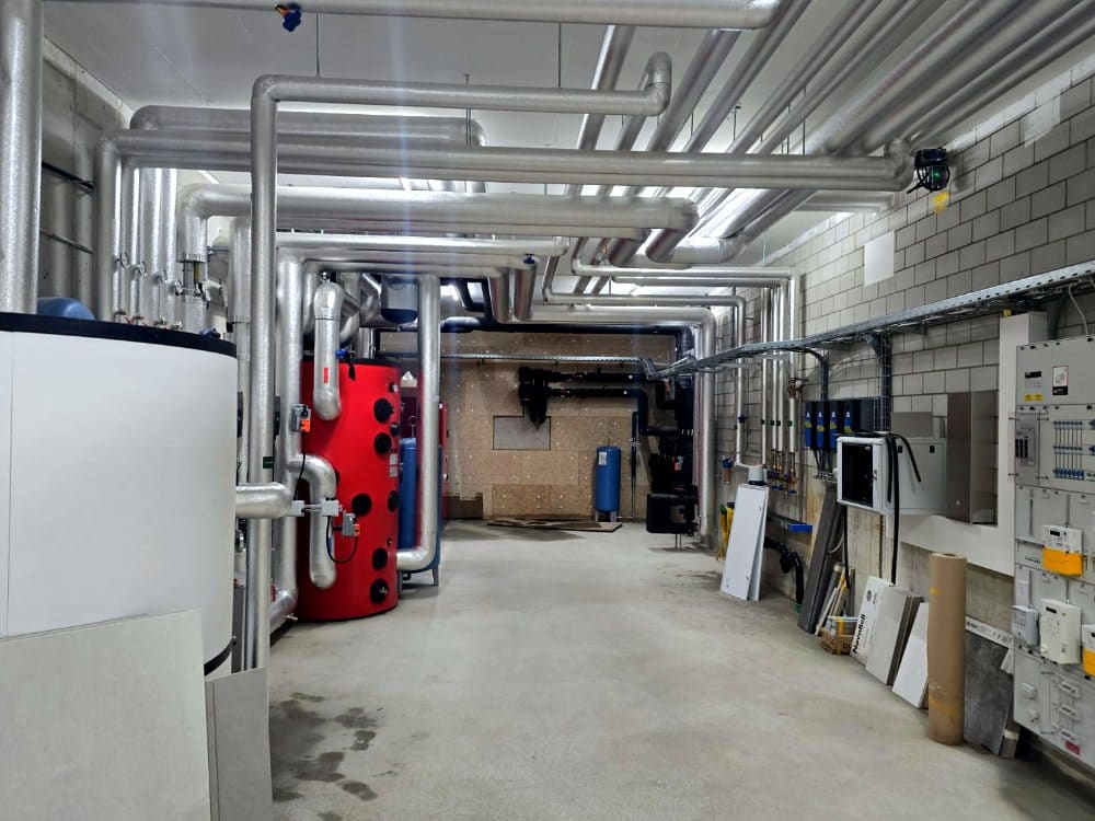 Heizzentrale mit isolierten Leitungen unter der Decke, Mehrfamilienhaus Zumikon